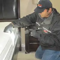 Bed bug inspection technician checking a mattress and bed frame for signs of infestation in Provo, UT