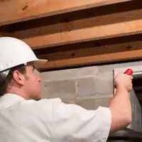 Termite inspection technician checking a basement wall and framing for termite activity in Provo, UT